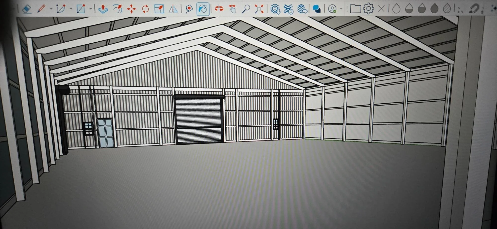 Steel-frame warehouse with corrugated metal siding, peaked roof, and roll-up doors
