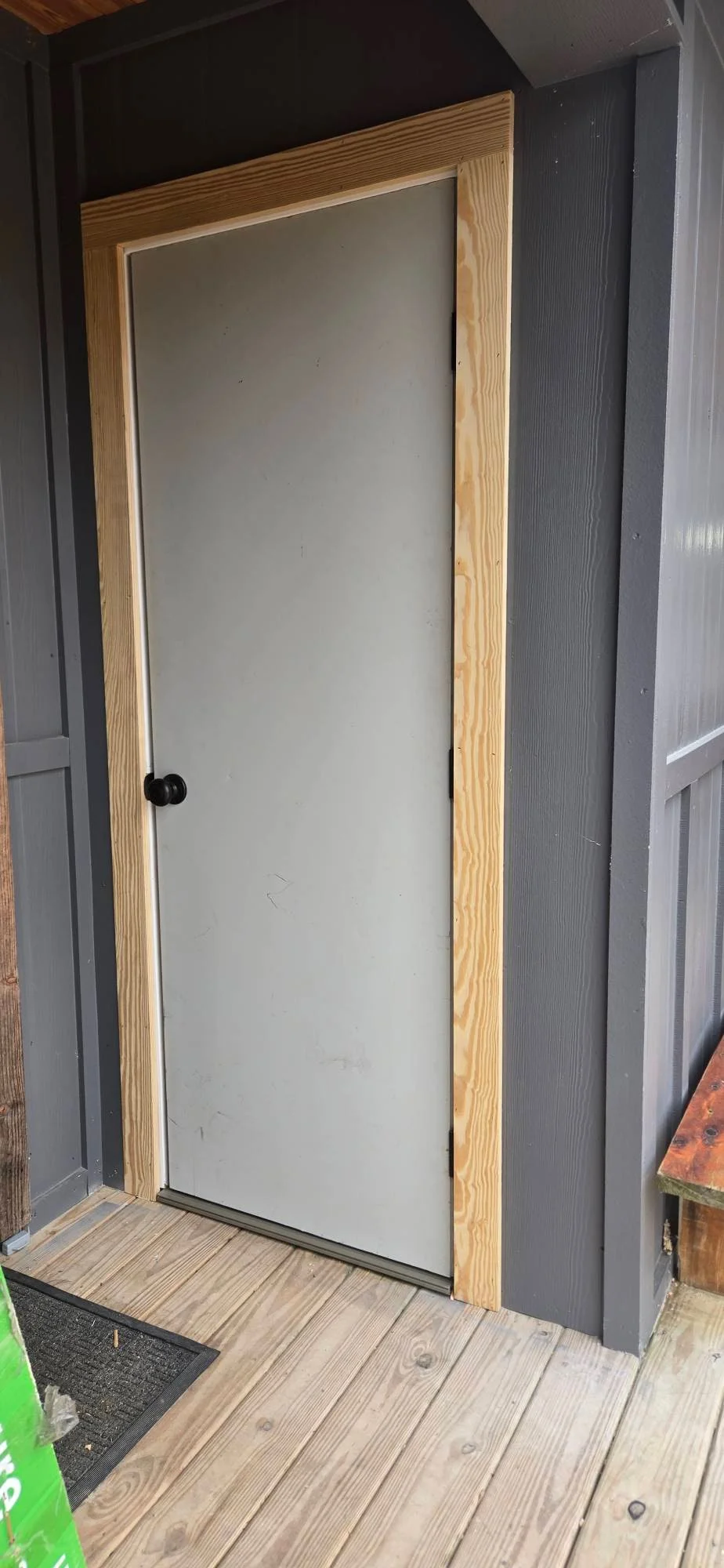 Wood-framed interior door with white panel and black knob in dark wall opening