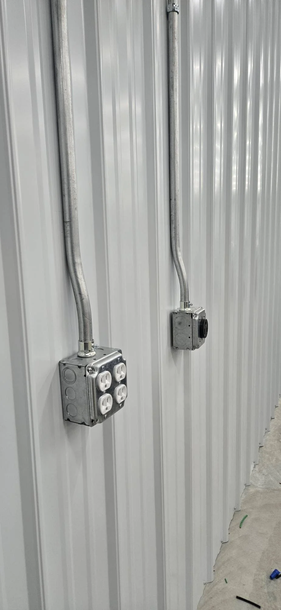 Metal conduit and electrical outlet boxes mounted on corrugated metal building wall