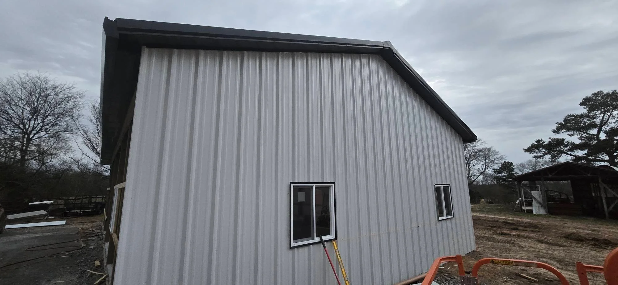 Metal building with corrugated steel siding, pitched roof, and black-framed windows