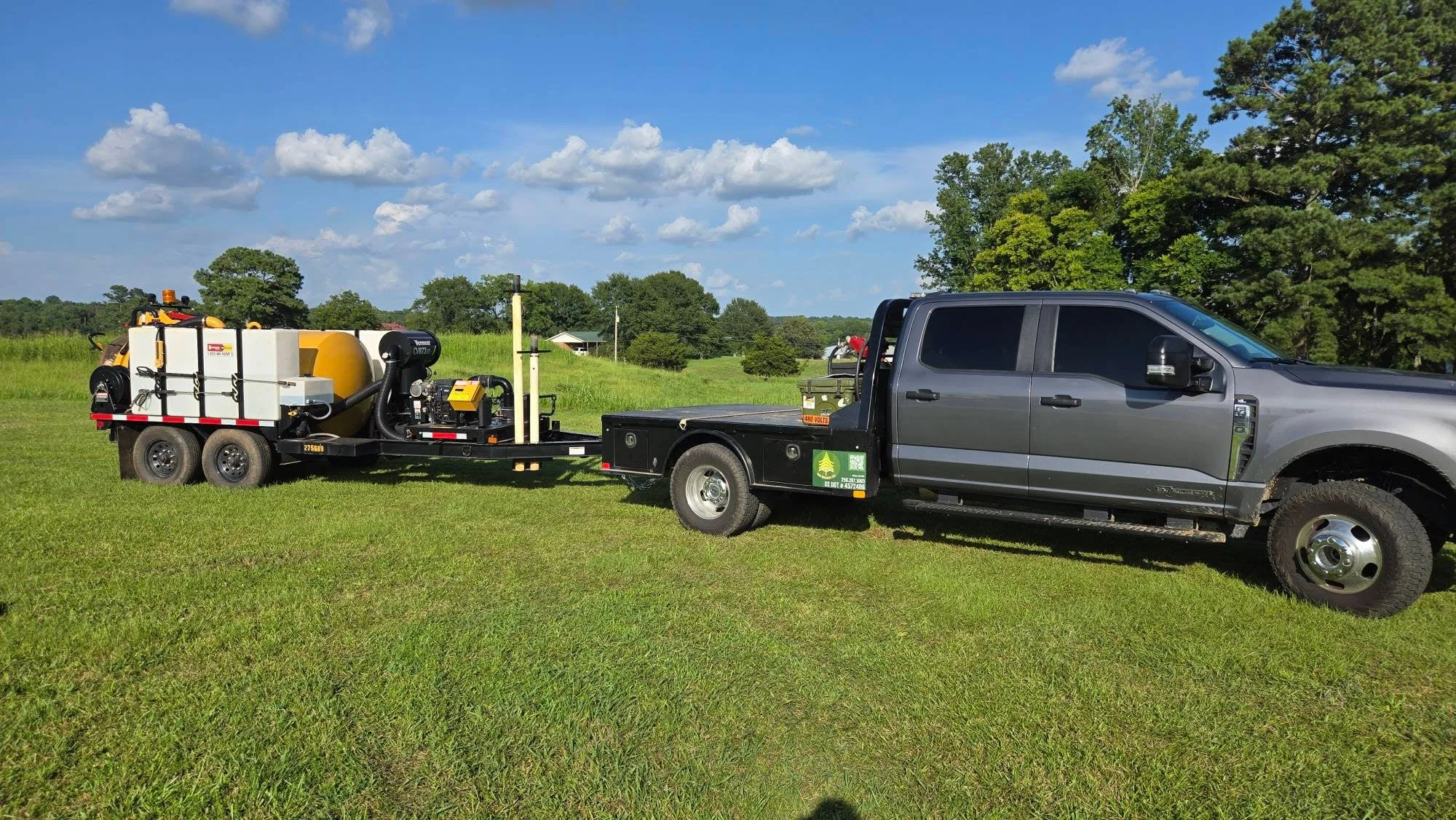 Dual-axle clearing trailer with hydraulic debris system and flatbed truck on cleared pasture