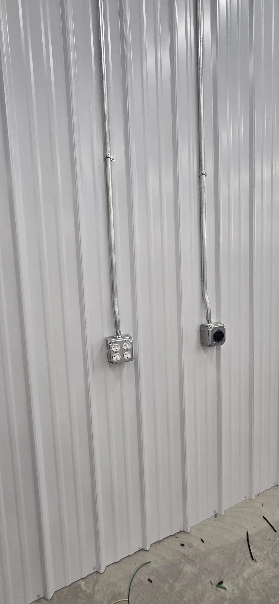Metal conduit and electrical outlets installed on corrugated metal building wall