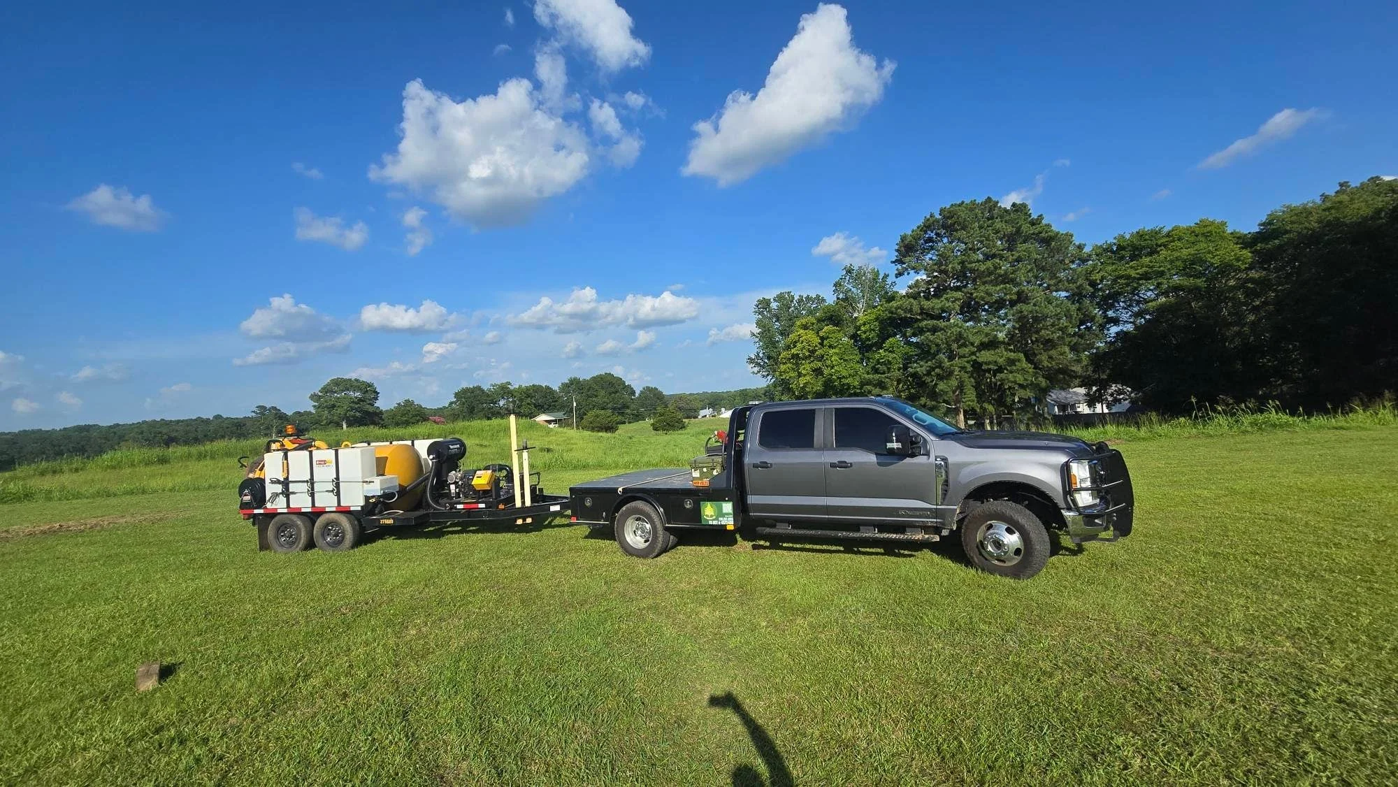 Hydraulic mulcher and flatbed truck on cleared pasture land with equipment setup