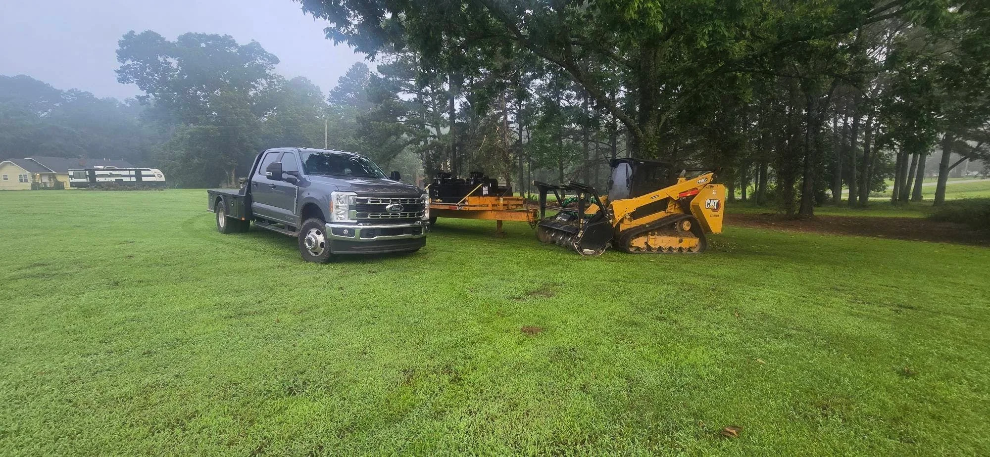 CAT track loader and grading equipment clearing residential property with mature trees